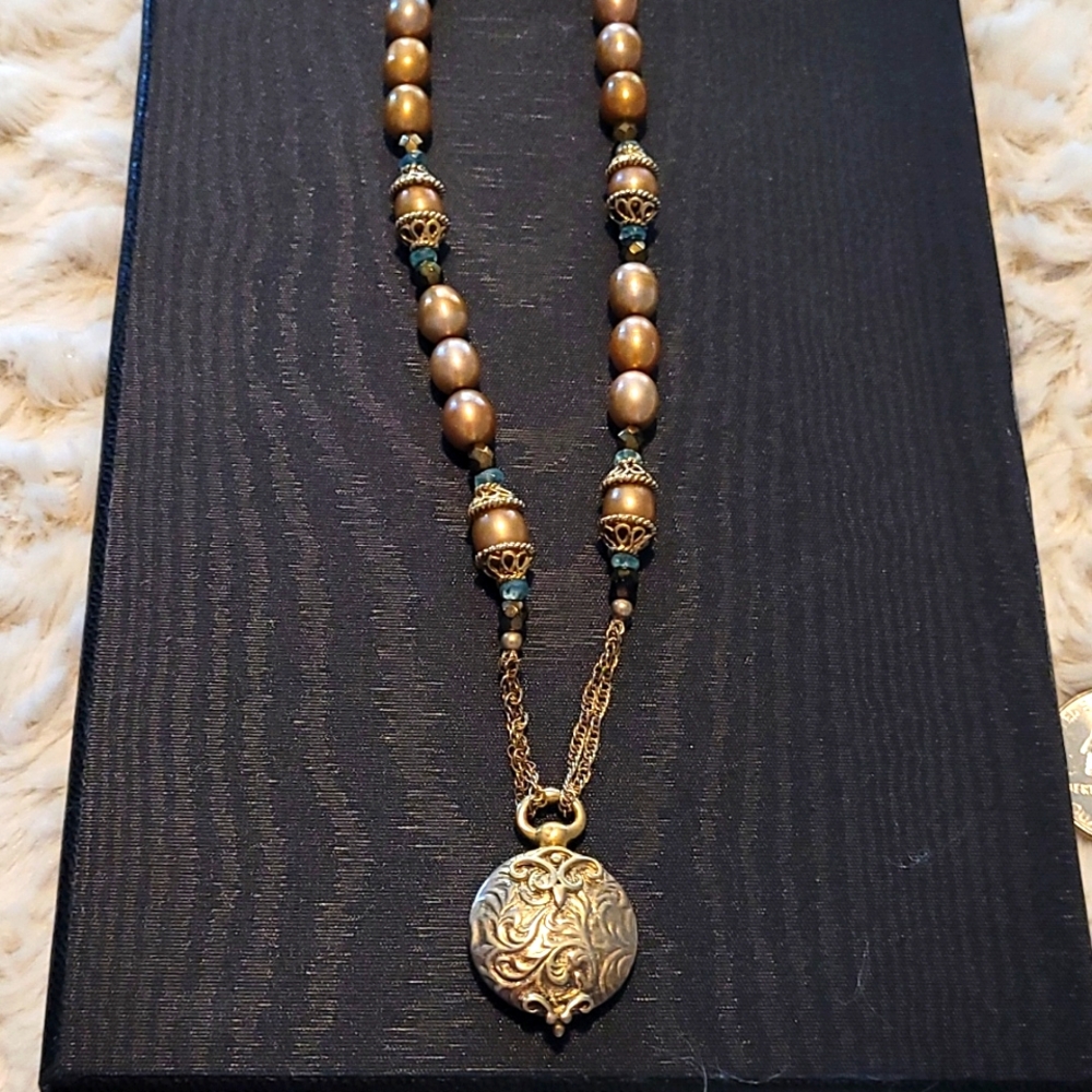 Goldtone pendant on necklace with golden pearls.